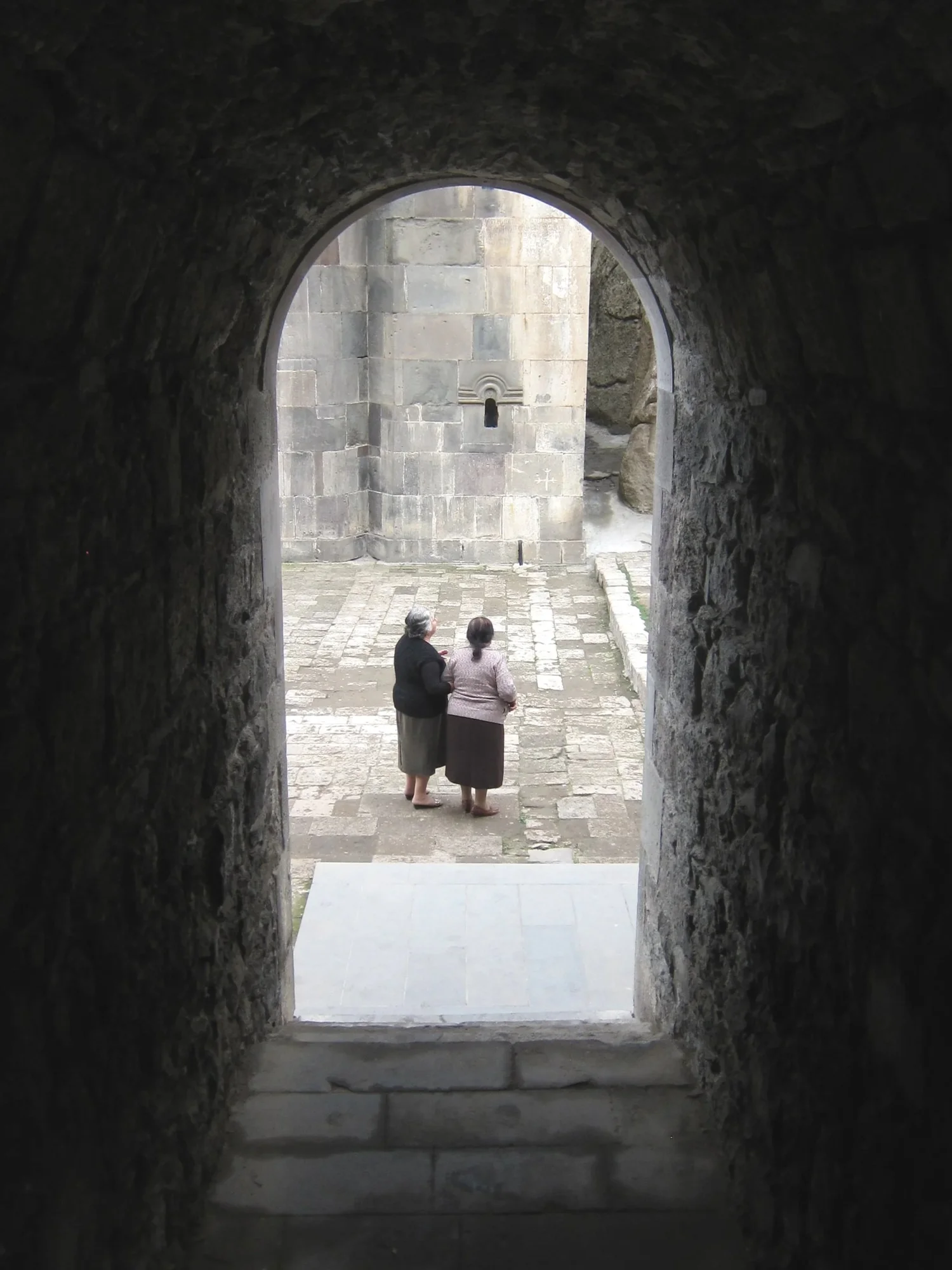 Two elderly Armenian women framed by a stone archway